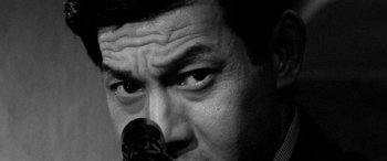 Movie still from “A Colt Is My Passport” (1967), directed by Takashi Nomura – Close up of a man's face with a microphone in front of him; Extreme Close Up shot, Low angle