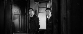 Movie still from “A Colt Is My Passport” (1967), directed by Takashi Nomura – Two men in suits standing in front of a window; Medium shot, Low angle