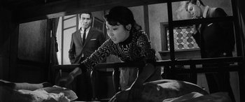 Movie still from “A Colt Is My Passport” (1967), directed by Takashi Nomura – A woman sitting on a chair next to a man; Medium shot, Over the shoulder angle