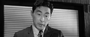 Movie still from “A Colt Is My Passport” (1967), directed by Takashi Nomura – Black and white photograph of a man wearing a suit; Close Up shot, Low angle