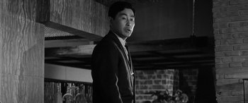 Movie still from “A Colt Is My Passport” (1967), directed by Takashi Nomura – Black and white photograph of a man in a suit; Close Up shot, Low angle