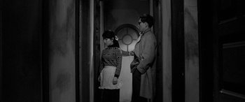 Movie still from “A Colt Is My Passport” (1967), directed by Takashi Nomura – A man and a woman standing next to each other in a doorway; Medium shot, High angle