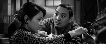 Movie still from “A Colt Is My Passport” (1967), directed by Takashi Nomura – A man and a woman looking at each other in black and white; Close Up shot, Over the shoulder angle