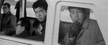 Movie still from “A Colt Is My Passport” (1967), directed by Takashi Nomura – A group of men sitting in the back of a truck; Close Up shot, Low angle