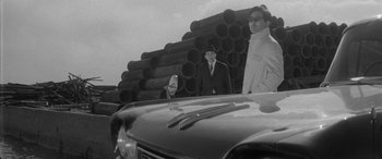 Movie still from “A Colt Is My Passport” (1967), directed by Takashi Nomura – A black and white photo of two men standing next to each other; Medium shot, Low angle