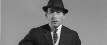 Movie still from “A Colt Is My Passport” (1967), directed by Takashi Nomura – An old black and white photo of a man in a suit and hat; Close Up shot, Low angle