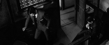 Movie still from “A Colt Is My Passport” (1967), directed by Takashi Nomura – A black and white photo of a man in a suit; Medium shot, Low angle