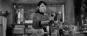Movie still from “A Colt Is My Passport” (1967), directed by Takashi Nomura – A woman is holding a knife in a restaurant kitchen; Medium shot, Low angle