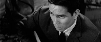 Movie still from “A Colt Is My Passport” (1967), directed by Takashi Nomura – Black and white photograph of a man in a suit and neck tie; Close Up shot, High angle