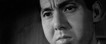 Movie still from “A Colt Is My Passport” (1967), directed by Takashi Nomura – Black and white photograph of a man's face looking at the camera; Extreme Close Up shot, Low angle