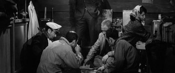 Movie still from “A Colt Is My Passport” (1967), directed by Takashi Nomura – A black and white photo of a group of men playing a game; Medium shot, High angle