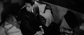 Movie still from “A Colt Is My Passport” (1967), directed by Takashi Nomura – A man in a suit sitting on the ground; Medium shot, High angle
