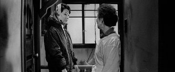 Movie still from “A Colt Is My Passport” (1967), directed by Takashi Nomura – Two women are standing in front of a window; Medium shot, Over the shoulder angle