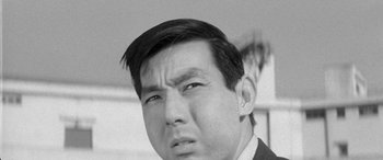 Movie still from “A Colt Is My Passport” (1967), directed by Takashi Nomura – Black and white photograph of a man in a business suit; Close Up shot, High angle
