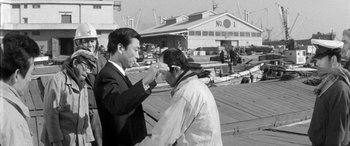 Movie still from “A Colt Is My Passport” (1967), directed by Takashi Nomura – A man in a business suit and a man in a business suit; Medium shot, Over the shoulder angle