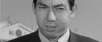 Movie still from “A Colt Is My Passport” (1967), directed by Takashi Nomura – Black and white photograph of a man in a business suit; Close Up shot, High angle