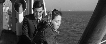 Movie still from “A Colt Is My Passport” (1967), directed by Takashi Nomura – A man and a woman on a boat in the water; Medium shot, High angle