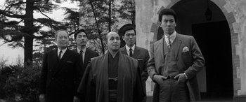 Movie still from “A Colt Is My Passport” (1967), directed by Takashi Nomura – A black and white photo of a group of men in suits; Medium shot, Low angle