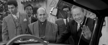 Movie still from “A Colt Is My Passport” (1967), directed by Takashi Nomura – A black and white photo of a man in a robe; Medium shot, Over the shoulder angle