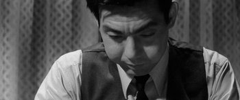Movie still from “A Colt Is My Passport” (1967), directed by Takashi Nomura – A black and white photo of a man looking down; Close Up shot, High angle