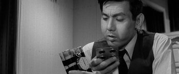 Movie still from “A Colt Is My Passport” (1967), directed by Takashi Nomura – A black and white photo of a man looking at a clock; Close Up shot, Low angle