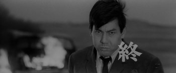 Movie still from “A Colt Is My Passport” (1967), directed by Takashi Nomura – Black and white photograph of a man in a suit; Close Up shot, Low angle