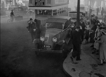 Movie still from “A Damsel in Distress” (1937), directed by George Stevens – An old photo of people standing next to an old car; Extreme Wide shot, High angle