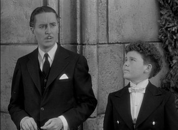 Movie still from “A Damsel in Distress” (1937), directed by George Stevens – A man and a boy in suits standing next to each other; Medium shot, Over the shoulder angle