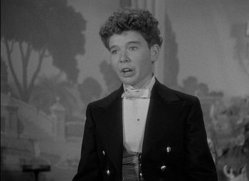 Movie still from “A Damsel in Distress” (1937), directed by George Stevens – A young man wearing a suit and bow tie in front of a painting; Close Up shot, High angle