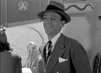 Movie still from “A Damsel in Distress” (1937), directed by George Stevens – A man in a suit and a hat smiling for the camera; Close Up shot, Over the shoulder angle