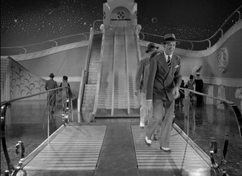 Movie still from “A Damsel in Distress” (1937), directed by George Stevens – A man in a suit and hat walking down a ramp; Wide shot, Low angle