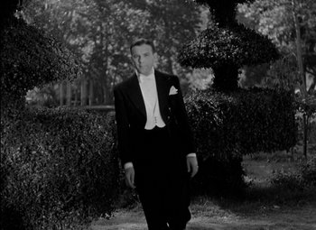 Movie still from “A Damsel in Distress” (1937), directed by George Stevens – A man in a tuxedo standing in front of bushes; Medium shot, High angle