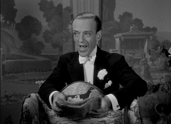 Movie still from “A Damsel in Distress” (1937), directed by George Stevens – A man in a suit and tie holding a bowl; Close Up shot, High angle