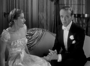 Movie still from “A Damsel in Distress” (1937), directed by George Stevens – A man and a woman sitting on a couch in formal wear; Medium shot, Over the shoulder angle