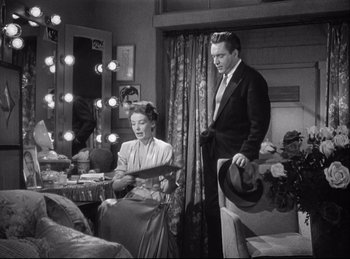 Movie still from “A Double Life” (1947), directed by George Cukor – A man and a woman are standing in front of a mirror; Medium shot, High angle