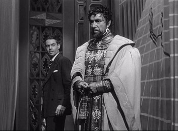 Movie still from “A Double Life” (1947), directed by George Cukor – A man standing next to another man in a suit; Medium shot, Low angle