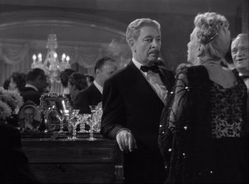 Movie still from “A Double Life” (1947), directed by George Cukor – An older man in a tuxedo talking to an older woman in an evening dress; Medium shot, Over the shoulder angle