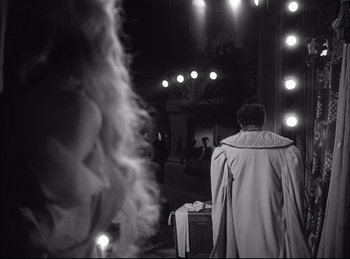 Movie still from “A Double Life” (1947), directed by George Cukor – A man standing in front of a mirror in front of lights; Medium shot, Over the shoulder angle