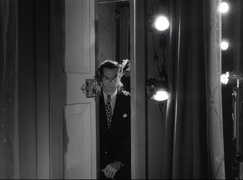 Movie still from “A Double Life” (1947), directed by George Cukor – A black and white photo of a man in a suit looking in a mirror; Medium shot, Low angle