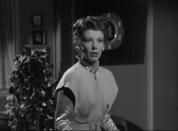 Movie still from “A Double Life” (1947), directed by George Cukor – A black and white photo of a woman in a dress; Medium shot, Low angle