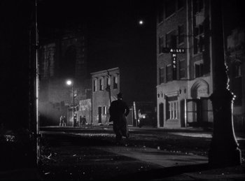 Movie still from “A Double Life” (1947), directed by George Cukor – A man standing on the side of a road at night; Extreme Wide shot, Over the shoulder angle