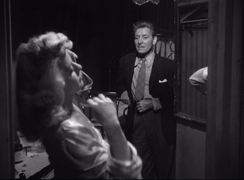 Movie still from “A Double Life” (1947), directed by George Cukor – A man and a woman are standing in front of a mirror; Medium shot, Over the shoulder angle
