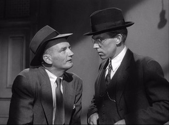 Movie still from “A Double Life” (1947), directed by George Cukor – A black and white photo of two men in suits and hats; Medium shot, Low angle