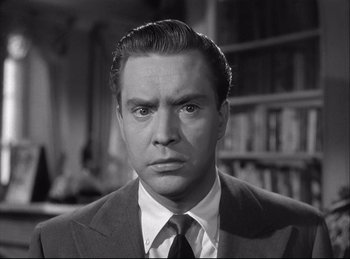 Movie still from “A Double Life” (1947), directed by George Cukor – A man wearing a suit and tie in front of a book shelf; Close Up shot, Low angle