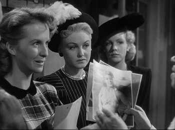 Movie still from “A Double Life” (1947), directed by George Cukor – A group of women standing next to each other holding papers; Medium shot, Over the shoulder angle