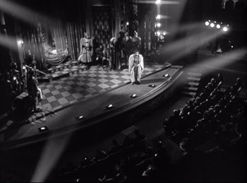 Movie still from “A Double Life” (1947), directed by George Cukor – An old photo of people on a stage; Extreme Wide shot, High angle