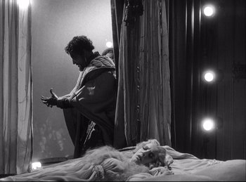 Movie still from “A Double Life” (1947), directed by George Cukor – A man sitting on top of a bed next to a dog; Wide shot, Low angle