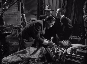 Movie still from “A Double Life” (1947), directed by George Cukor – A group of men standing around a man laying in a bed; Medium shot, High angle