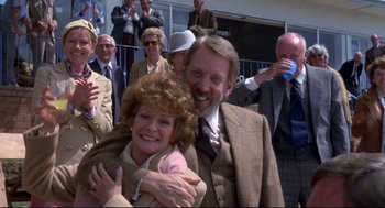 Movie still from “A Dry White Season” (1989), directed by Euzhan Palcy – A man and a woman hugging in front of a crowd; Medium shot, Low angle