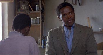 Movie still from “A Dry White Season” (1989), directed by Euzhan Palcy – A man and a woman are standing in a kitchen; Close Up shot, Over the shoulder angle